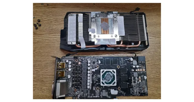 Placa de video desarmada sobre la mesa de trabajo, con el disipador separado del circuito para limpiarlo